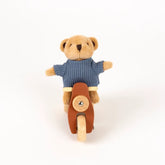 Kuschelbär in blauem Strickpullover auf Holzmotorrad, nachhaltiges Spielzeug für Kinder