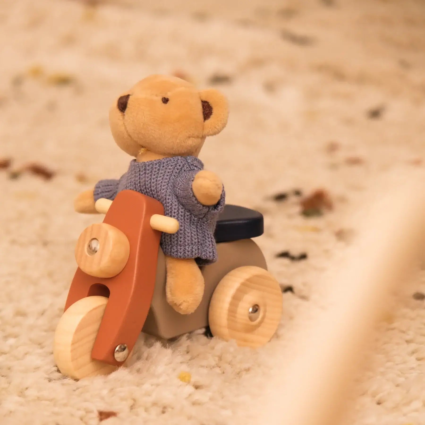 Kuschelbär in Strickpullover auf Holzmotorrad – nachhaltiges Spielzeug für Kinder