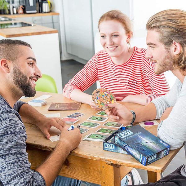 Freunde spielen gemeinsam das Escape-Room-Spiel EXIT am Holztisch, nachhaltiges Gesellschaftsspiel für Erwachsene