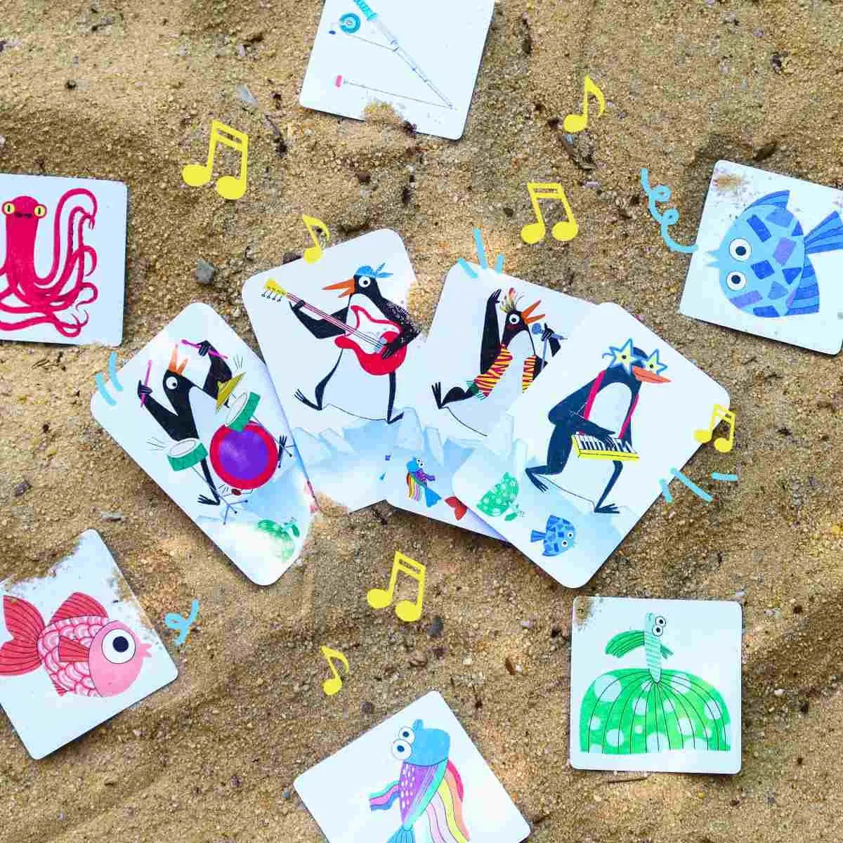 Bunte Spielkarten mit musizierenden Tieren auf Sand, ideal für kinderfreundliches, nachhaltiges Spielzeug